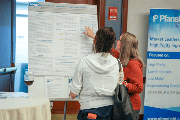Conference attendees discussing peptide therapeutics research during a poster presentation session