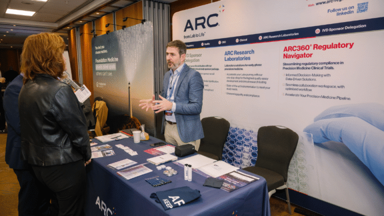Sponsor representative speaking with conference attendees at an exhibition booth.