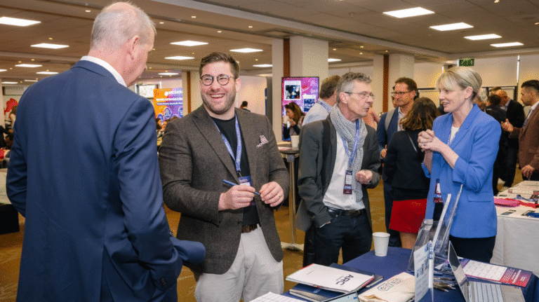 Conference delegates visiting sponsor booths at a peptide therapeutics industry exhibition.