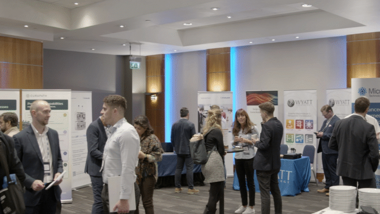 Sponsor representative speaking with conference attendees at an exhibition booth.